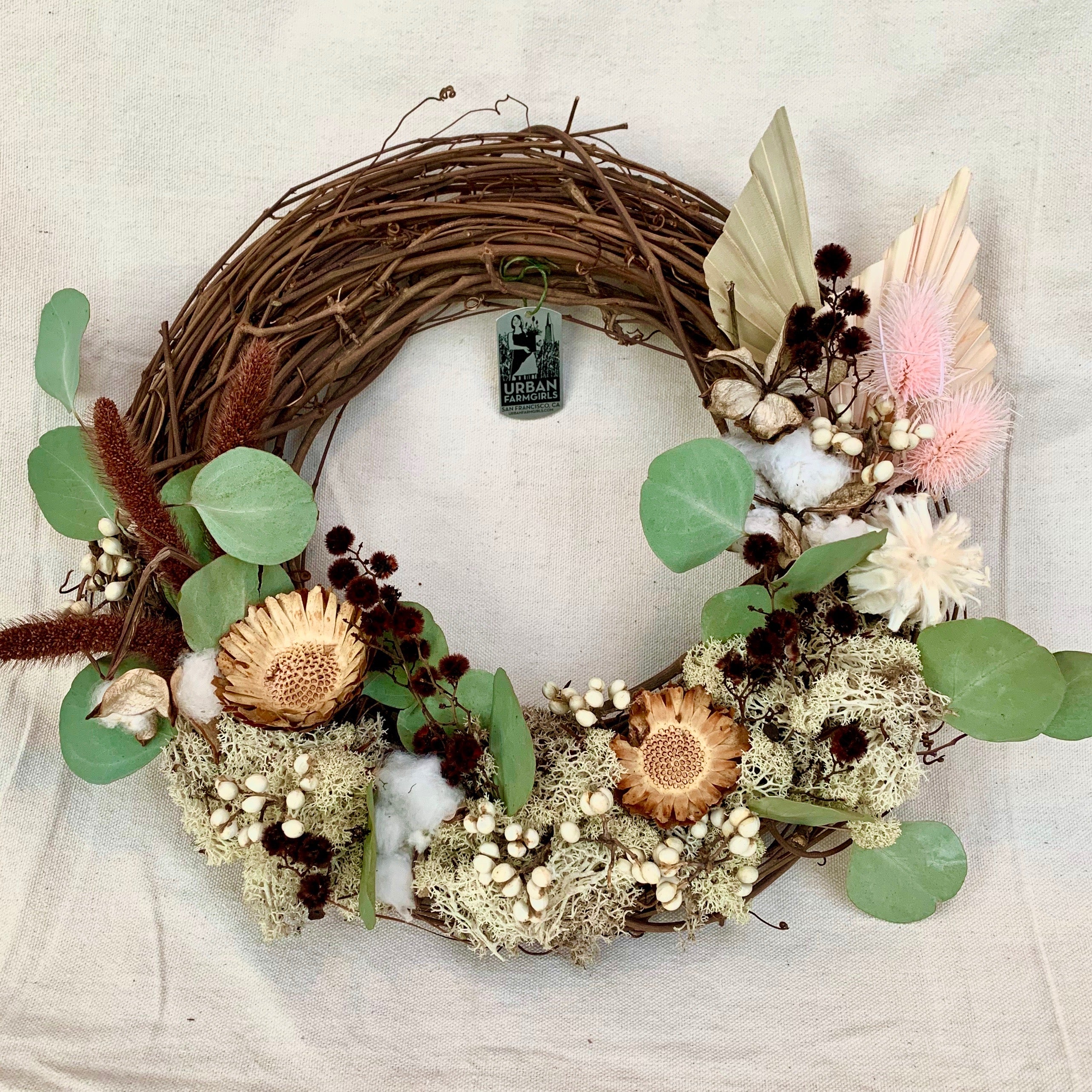 Inspired by crisp morning walks, this lightweight 12'' wreath combines dry elements of eucalyptus, tallow berries, foxtail reeds, palm fronds, and moss. The shades of green and bone with pops of pale yellow and pink create an elegant winter-bright design. Adorn your front door or anywhere in the home for any season.